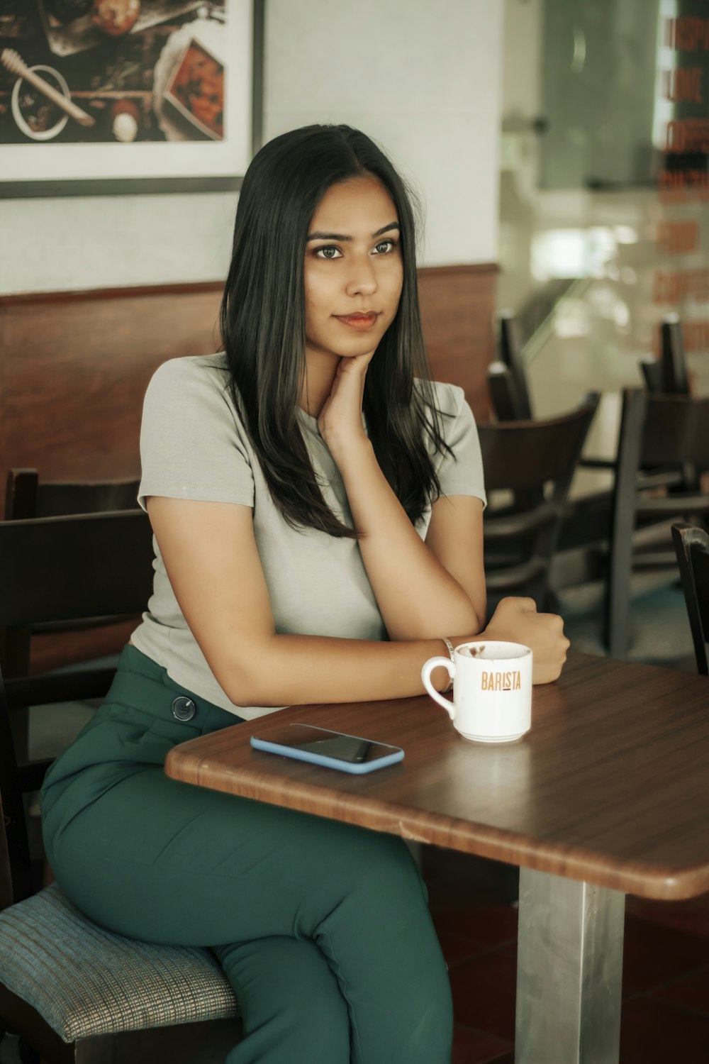 woman in white t-shirt sitting on brown wooden bench holding white ceramic mug