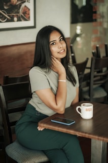 Lifestyle shot of a woman enjoying coffee at a chic café, wearing a rose gold accessory from Lumina Atelier