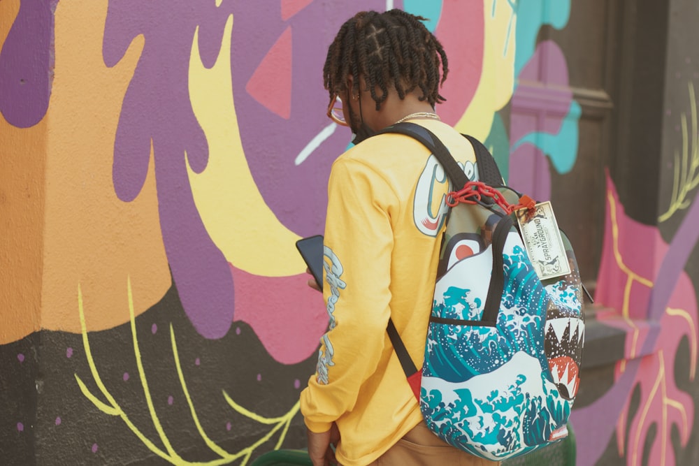 woman in yellow jacket standing beside wall with graffiti