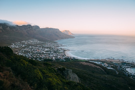 green mountain beside body of water during daytime in Camps Bay South Africa