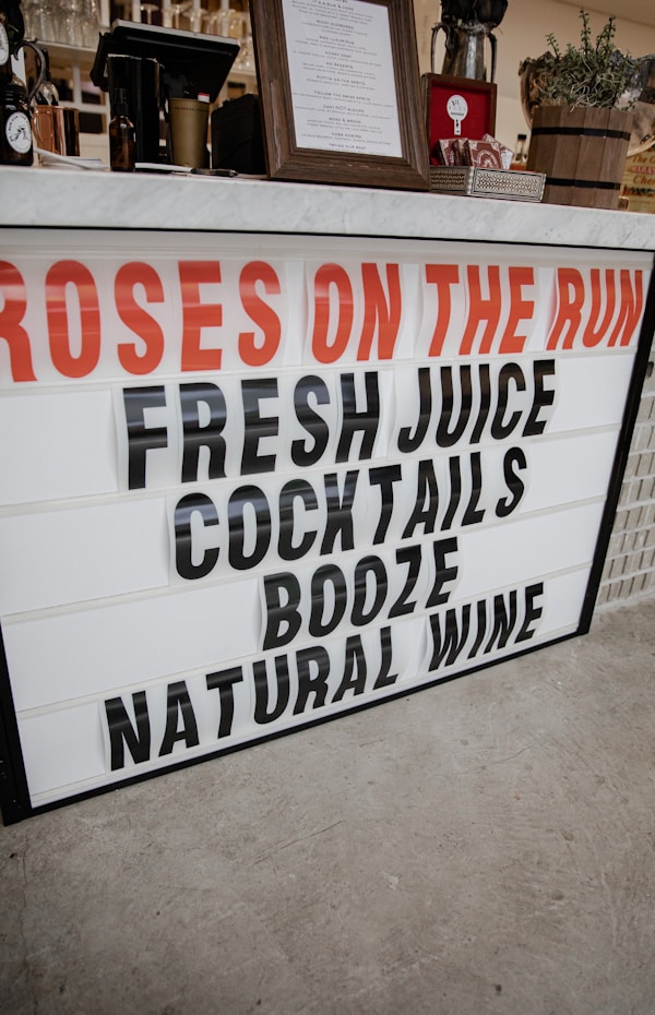A sign that says roses on the run fresh juice cocktails booze natural wine