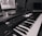 A monochrome image of a music production setup featuring a laptop displaying music software and a MIDI keyboard with various controls and buttons. The setup suggests a focus on electronic music production.