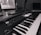 A monochrome image of a music production setup featuring a laptop displaying music software and a MIDI keyboard with various controls and buttons. The setup suggests a focus on electronic music production.