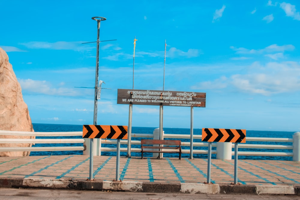 white and red wooden signage near sea during daytime