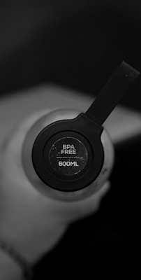 A close-up of a hand holding a compact water purifier bottle with clear water inside.