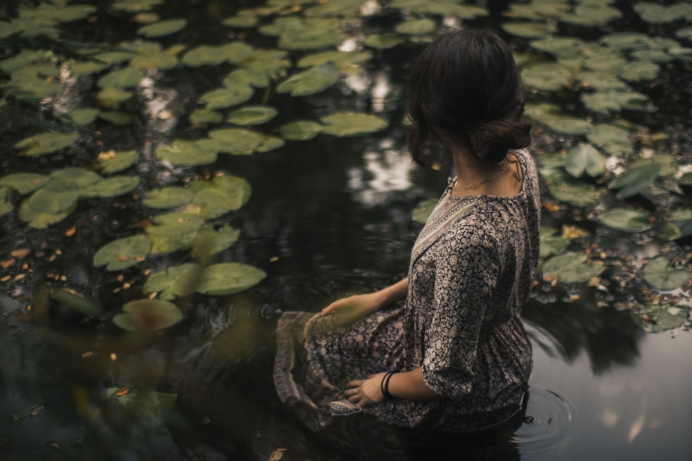 mulher no vestido floral preto e branco sentado na água