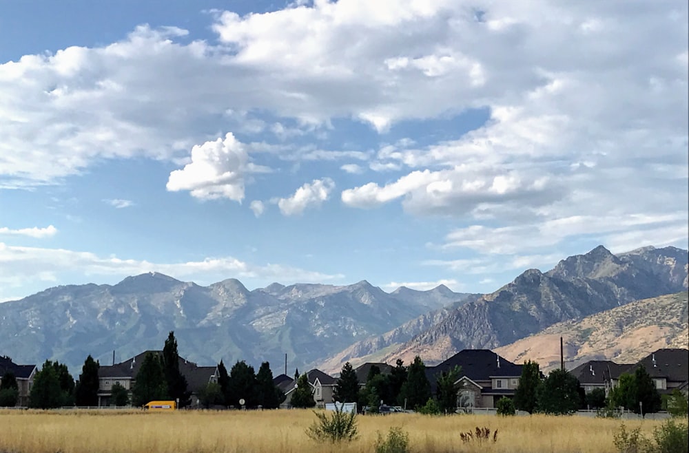 green grass field near mountains under white clouds during daytime