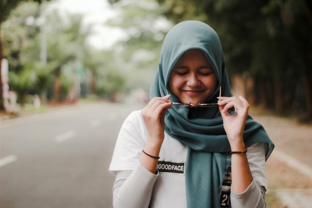 a woman in a hijab smiles while holding a camera