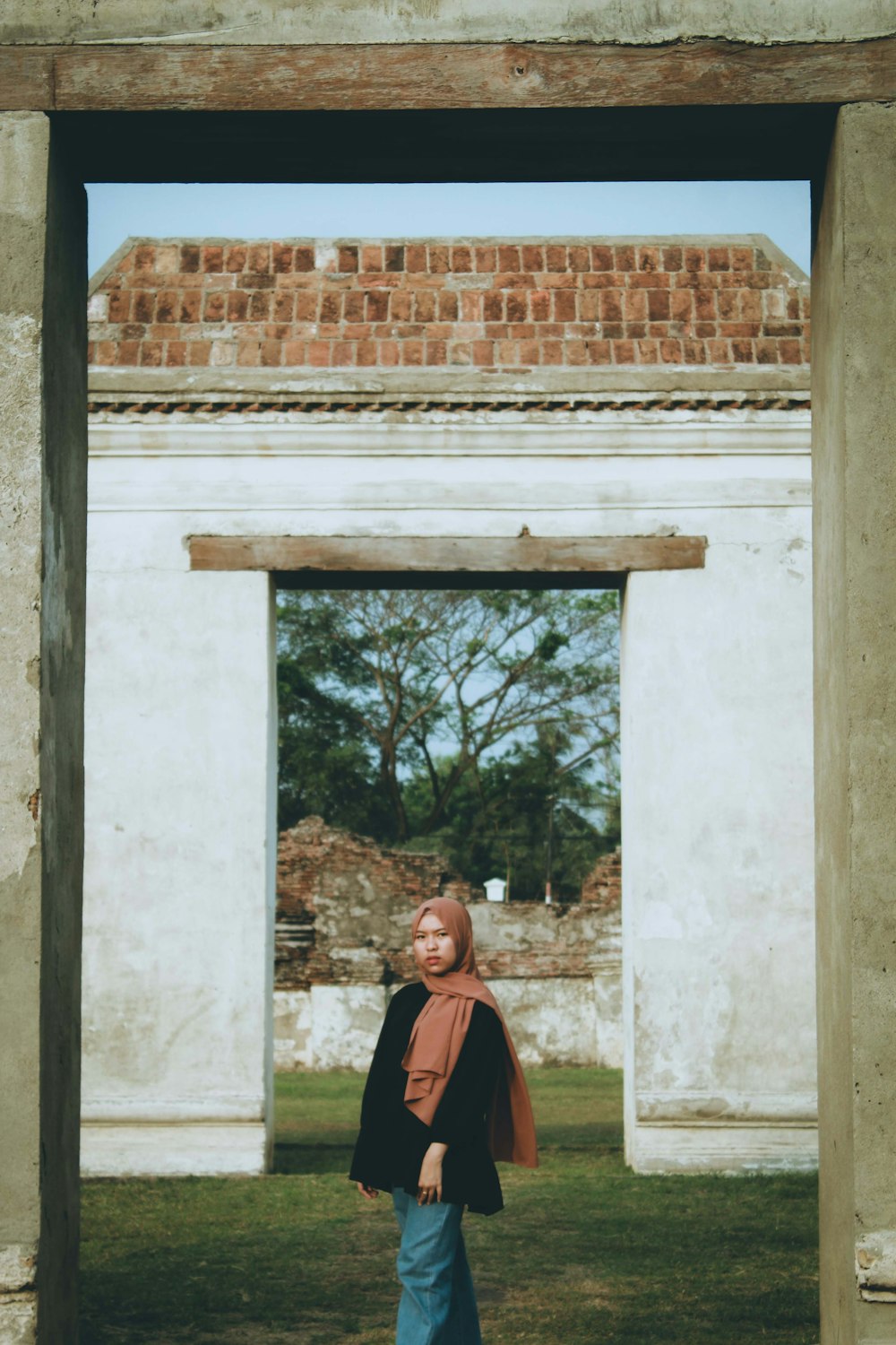 man in black and orange jacket standing near brown brick wall