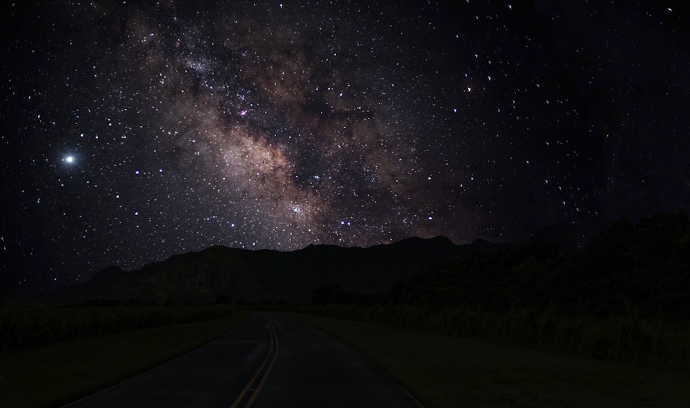 black asphalt road under starry night