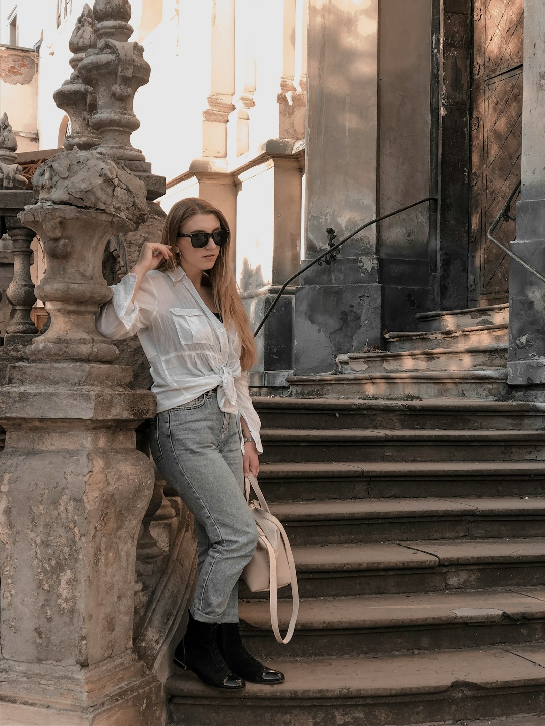 woman in white long sleeve shirt and gray pants sitting on brown concrete staircase