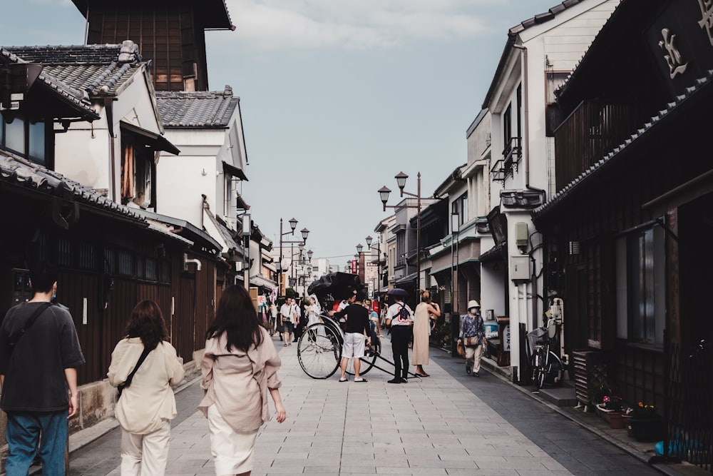 a group of people walking down a street next to tall buildings