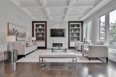 A living room with a marble fireplace, white sofas, and dark wood shelving