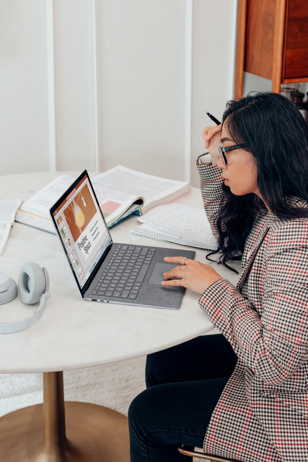 A professional reviewing notes beside a laptop at home.