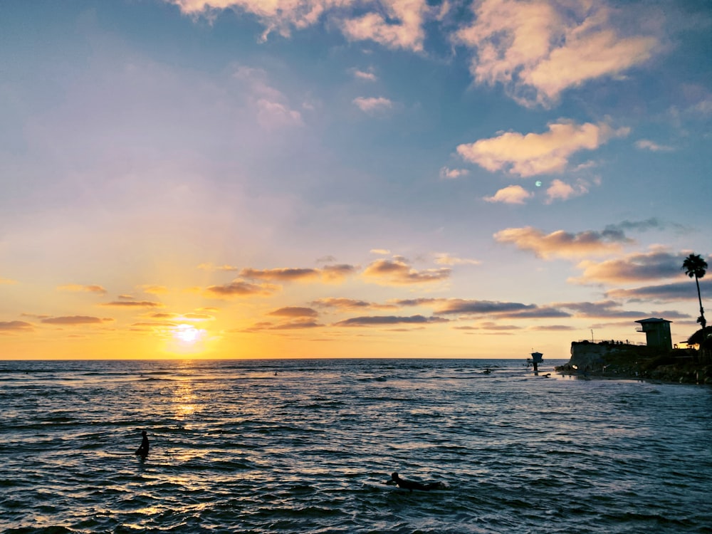 silhouette of people on sea during sunset