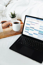 person holding white ceramic mug in front of black laptop computer