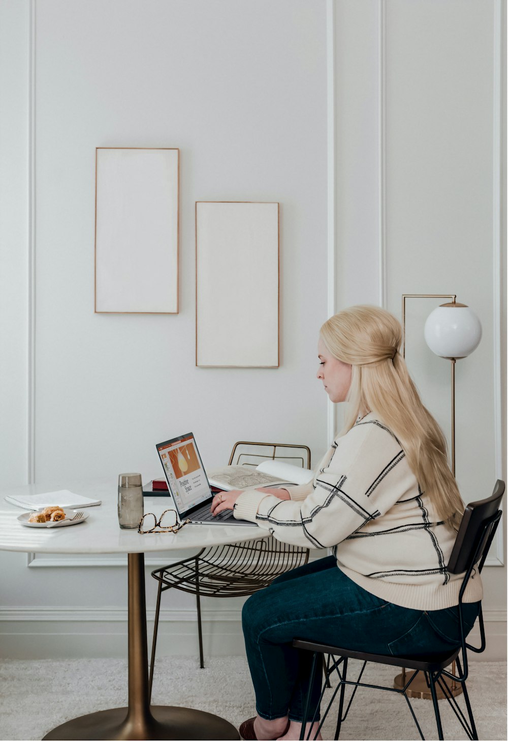 ノートパソコンの前の椅子に座る白い長袖シャツの女性