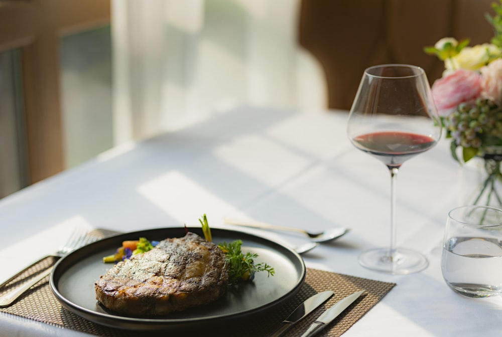 cooked food on white ceramic plate beside wine glass on table