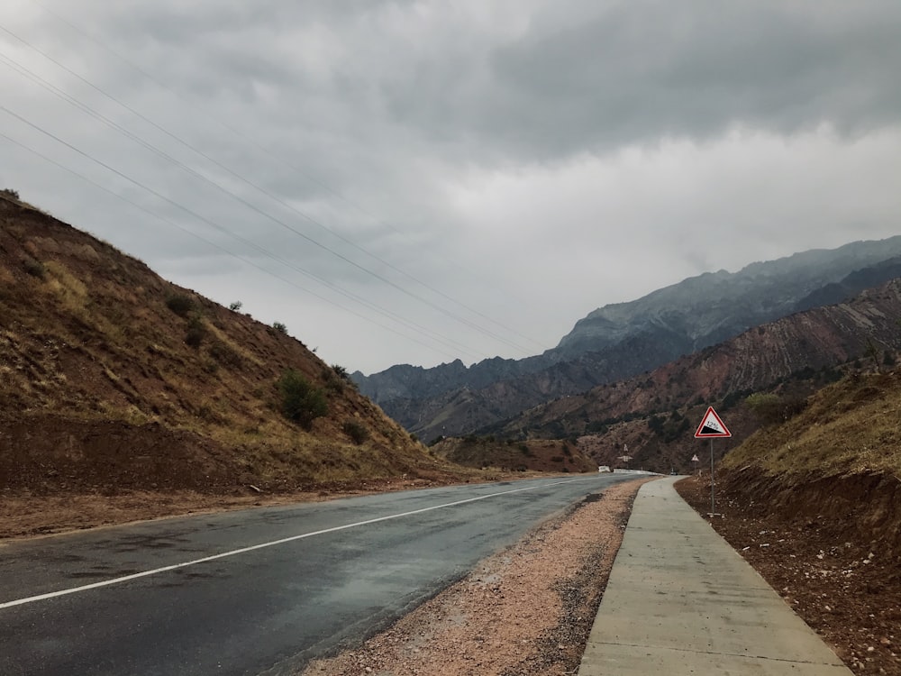 灰色の空の下の山の近くの灰色のコンクリート道路