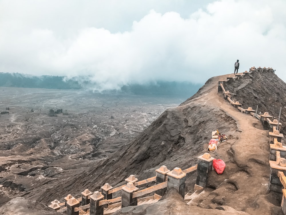 2 person standing on rocky hill during daytime