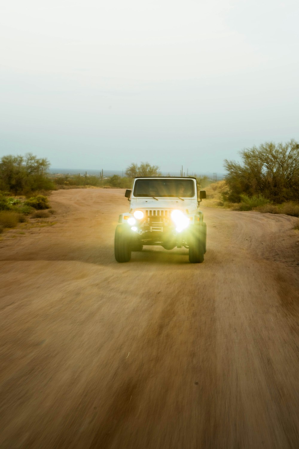 white car on brown dirt road during daytime