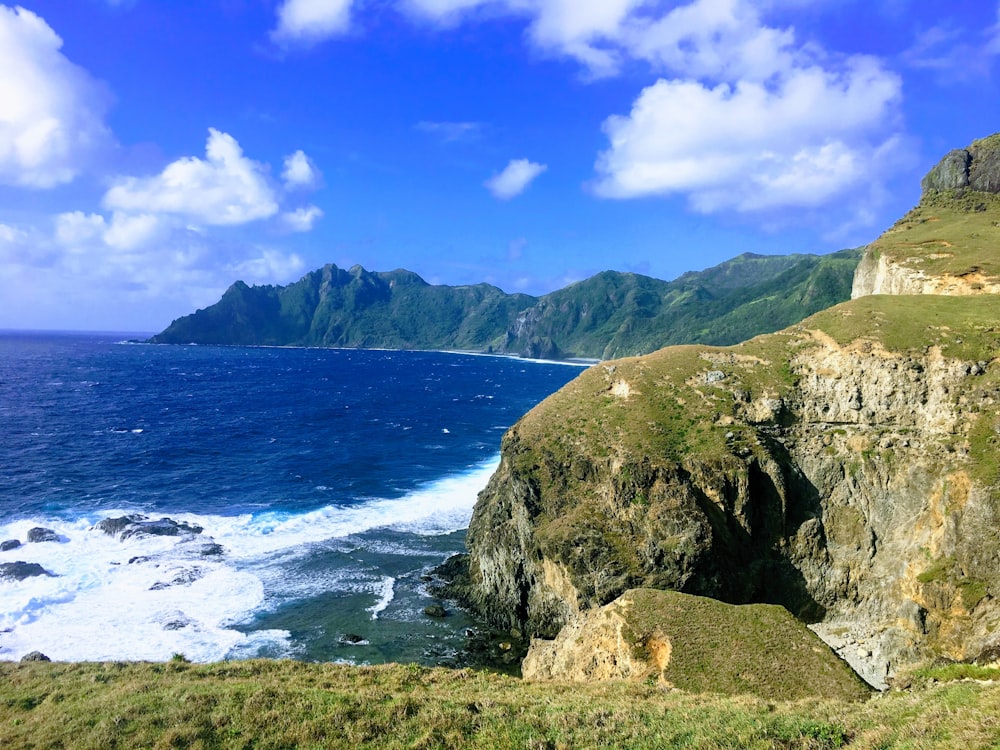 green mountain beside body of water during daytime