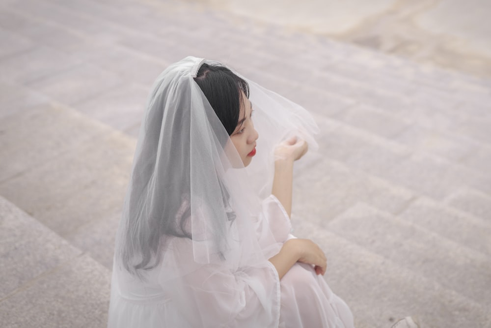 woman in white dress sitting on white sand during daytime