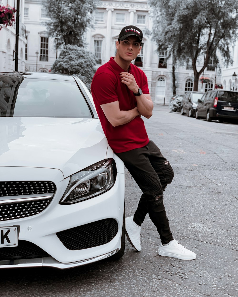 man in red polo shirt and black pants standing beside white mercedes benz car during daytime