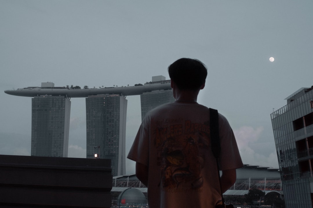 man in red and black crew neck t-shirt standing near body of water during daytime