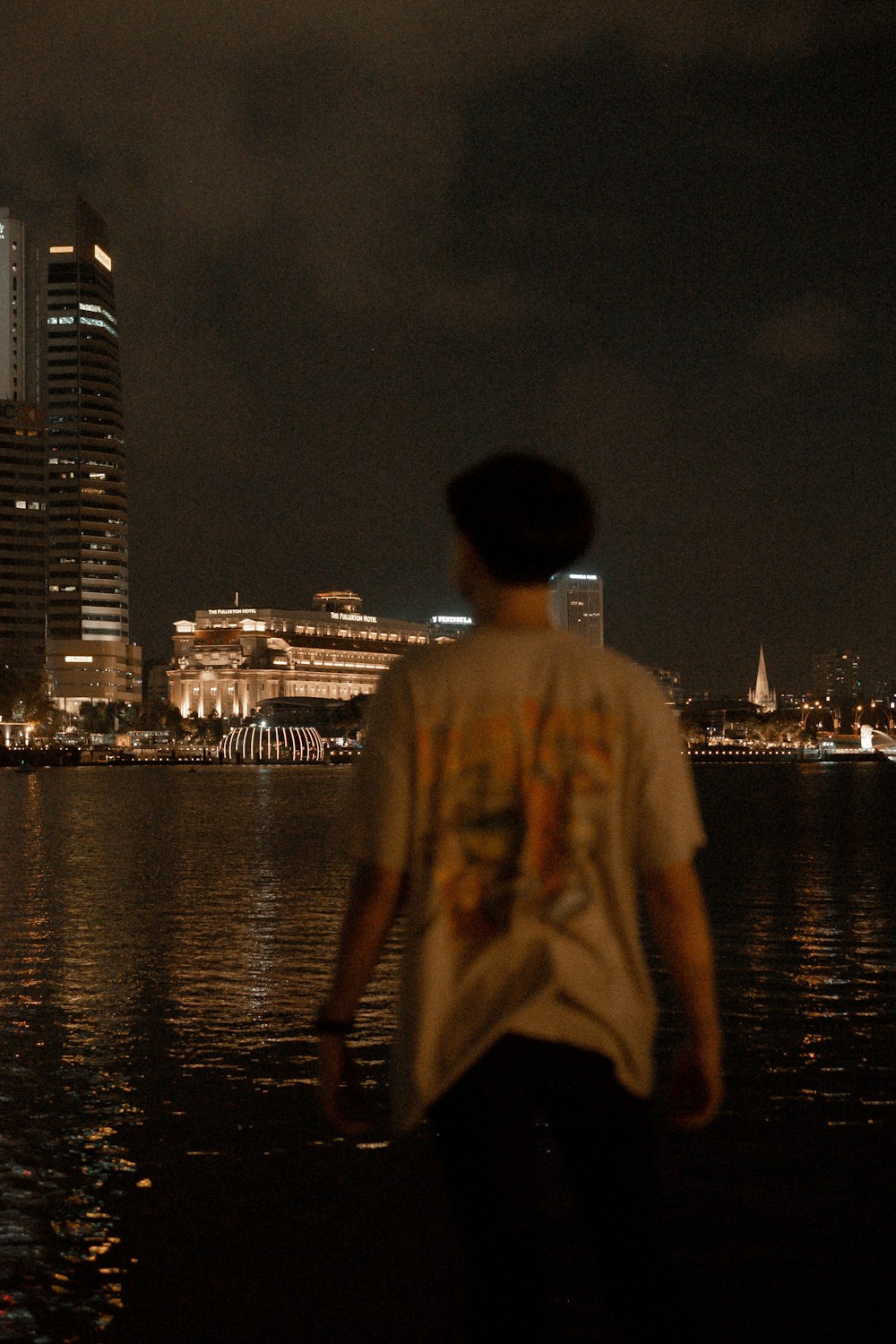 man in yellow dress standing near body of water during night time