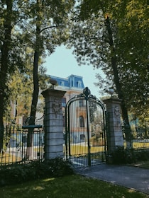 A grand automatic entry gate opening to a spacious driveway surrounded by greenery.