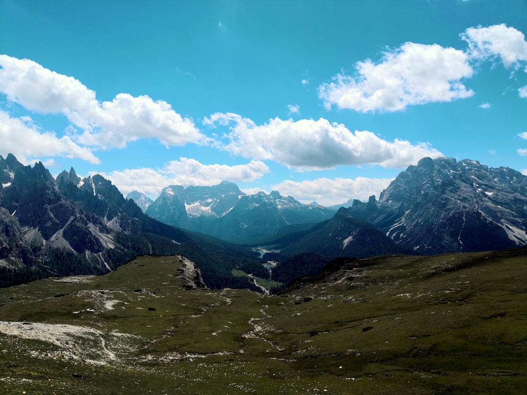 green grass field and mountains under blue sky during daytime