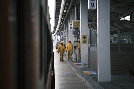 Construction workers in yellow and black uniforms inspecting a large industrial site.