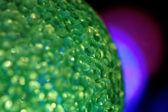 Close-up of translucent eco-friendly polymer pellets with a green leaf background.