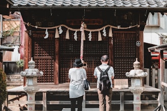 man in black and white jacket standing near brown wooden gate during daytime