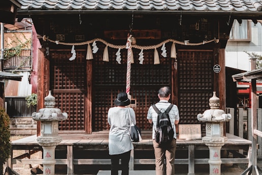 man in black and white jacket standing near brown wooden gate during daytime