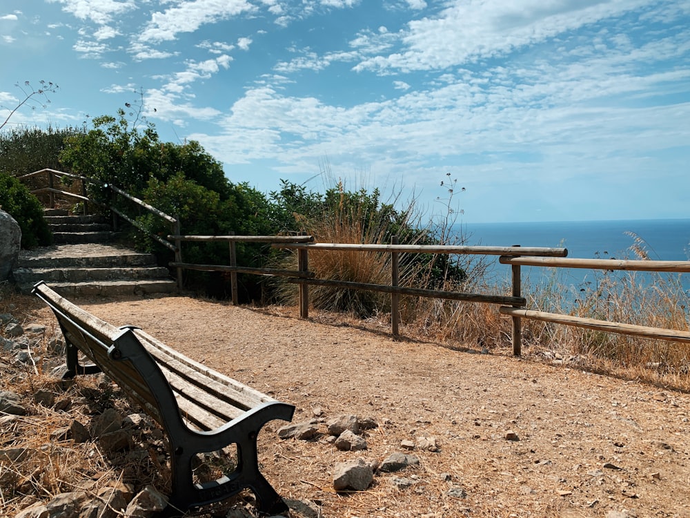 brown wooden bench on brown sand near body of water during daytime