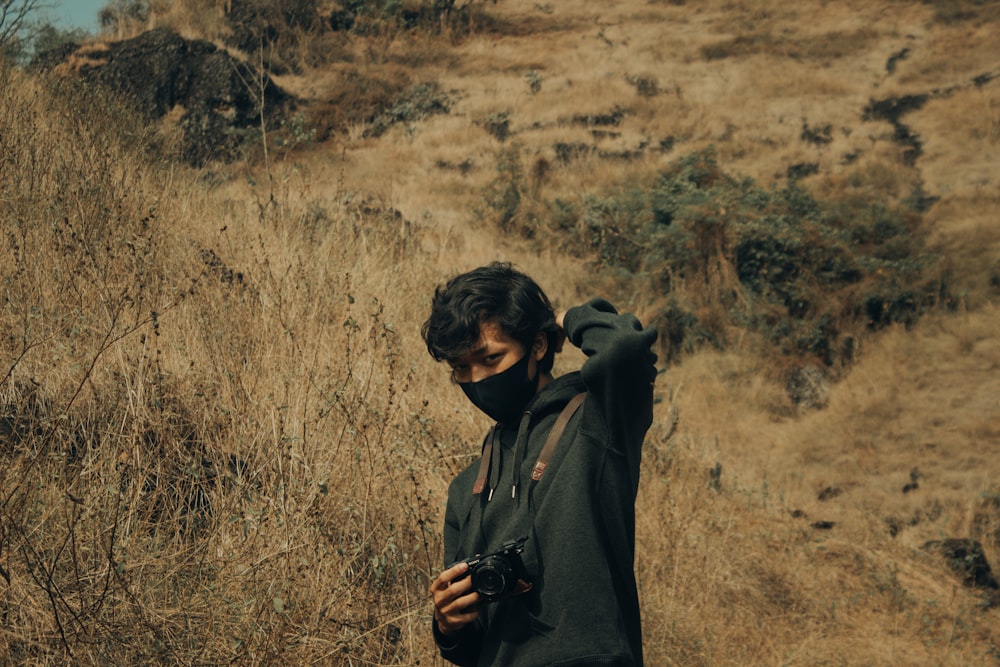 man in black hoodie standing on brown grass field during daytime