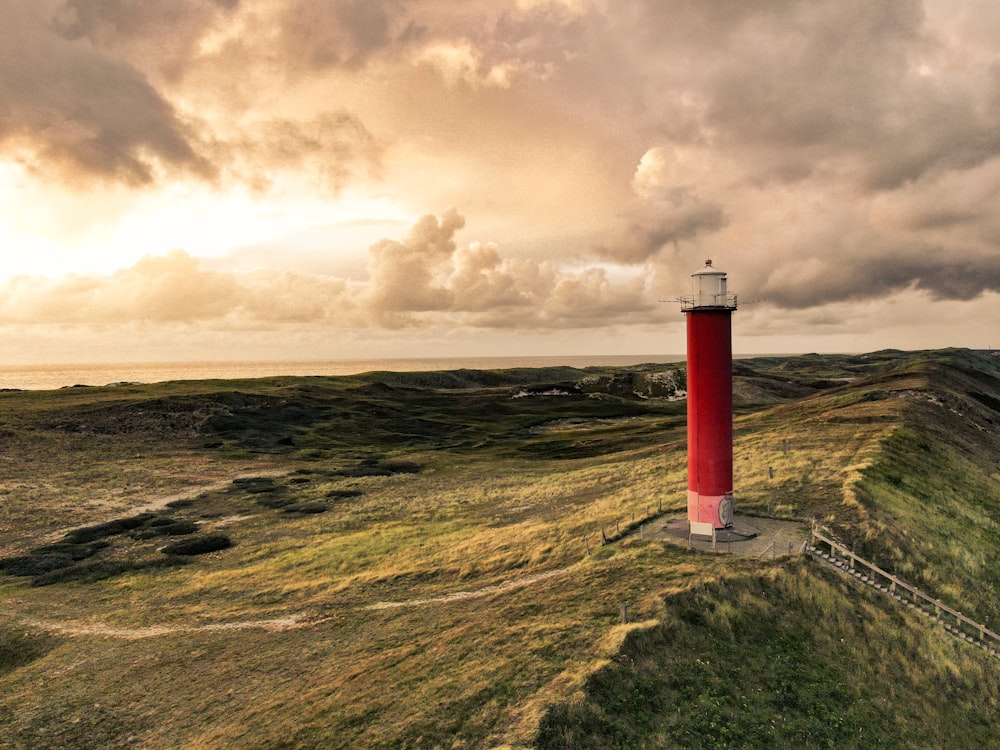 red and white lighthouse on green grass field under cloudy sky during daytime