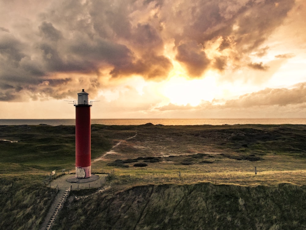 red and white lighthouse on brown hill during sunset