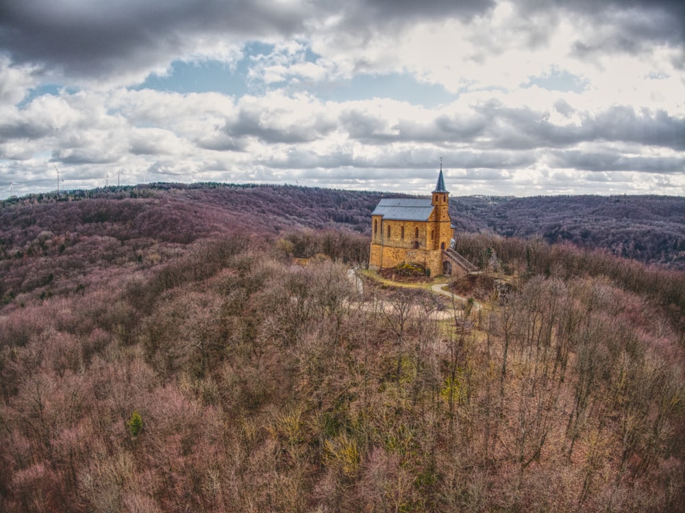 Braunes und grünes Haus auf grünem Rasenfeld unter weißen Wolken und blauem Himmel tagsüber