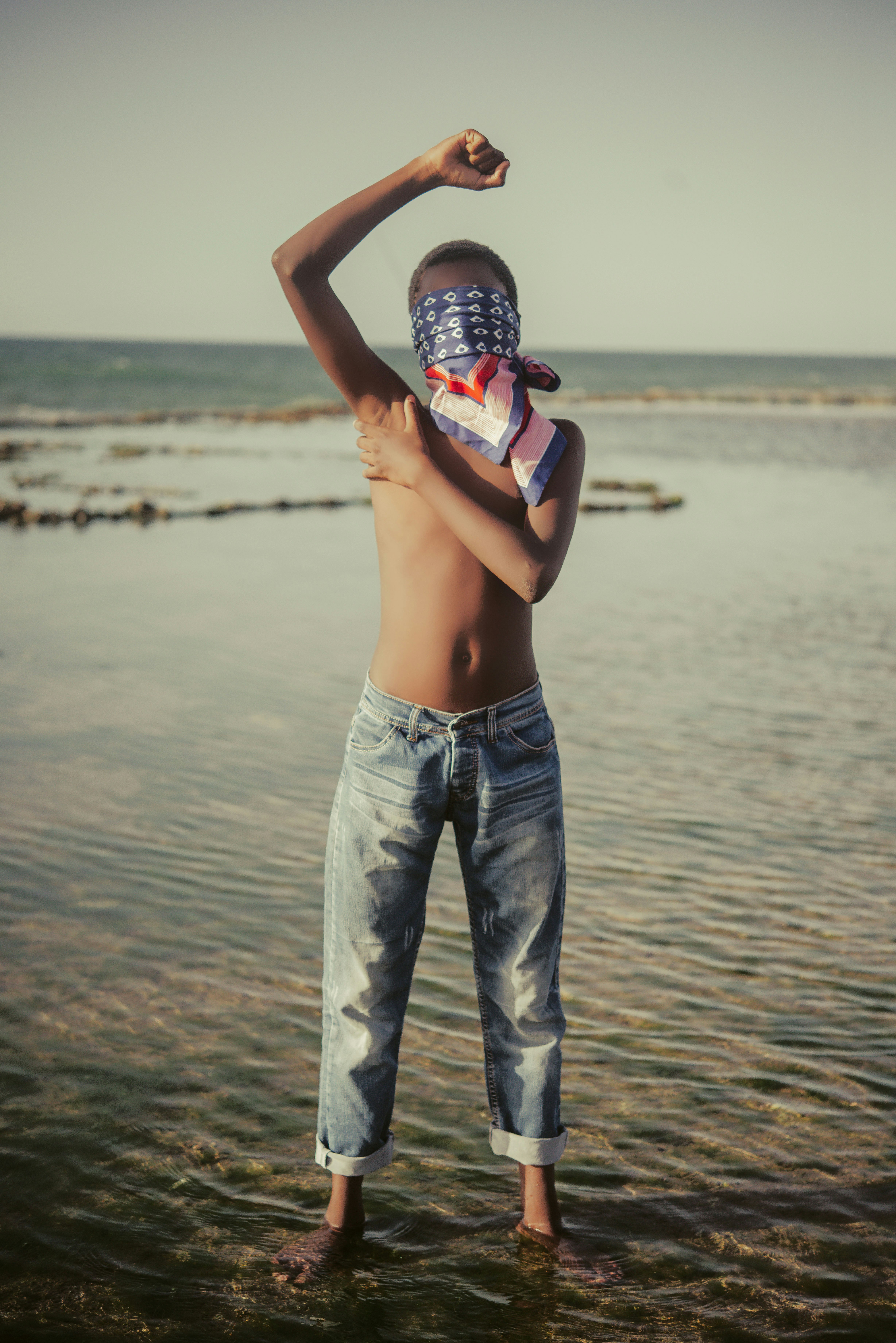 topless man in blue denim jeans holding white and blue plastic bottle