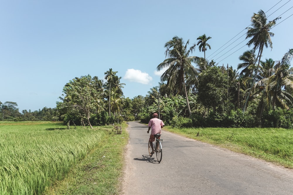 man in black shirt riding bicycle on road during daytime