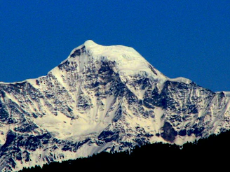 A majestic Alaskan mountain peak dusted with fresh snow under a clear blue sky.