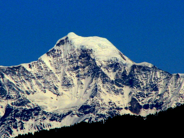 A majestic Alaskan mountain peak dusted with fresh snow under a clear blue sky.