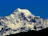 A close-up shot of a shimmering ice mountain peak under a clear blue sky.