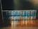 A neatly arranged collection of books with identical dark blue covers and gold lettering sits on a wooden shelf. Each book is uniformly positioned, creating a visually appealing display.