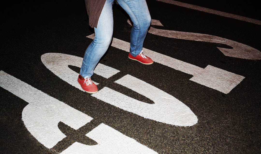 person in blue denim jeans and red sneakers