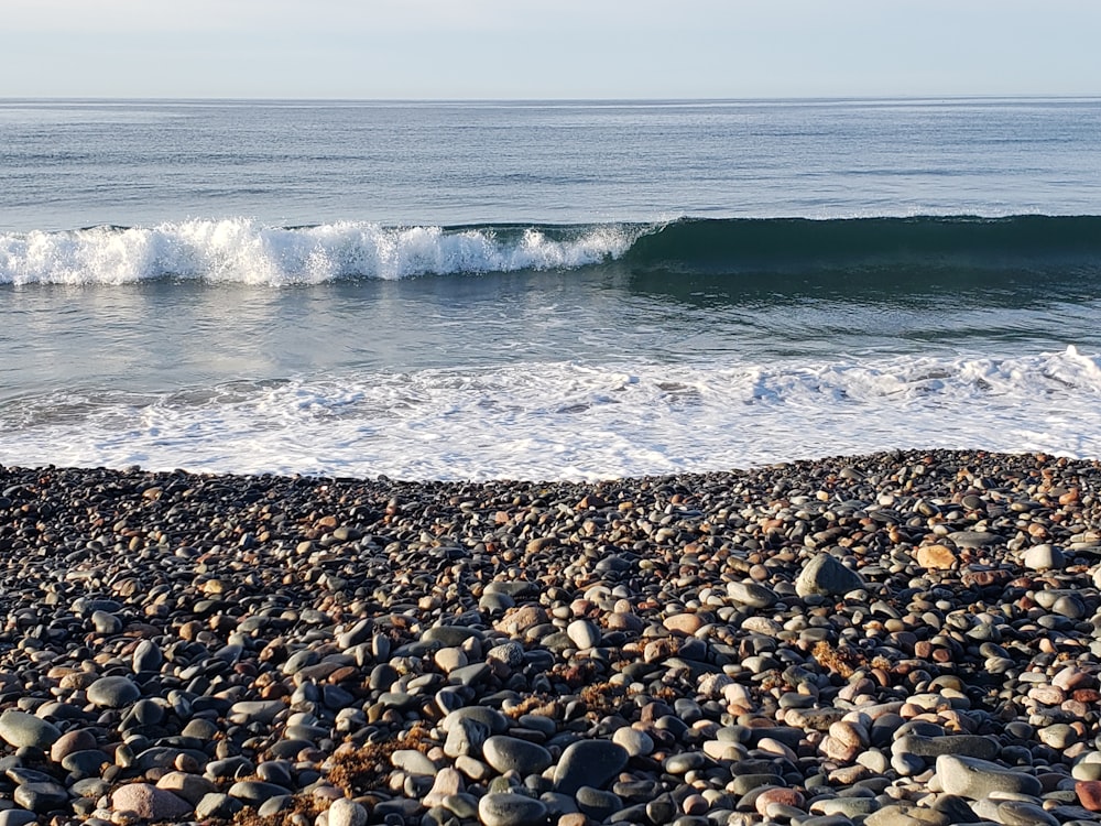 sea waves crashing on rocks during daytime