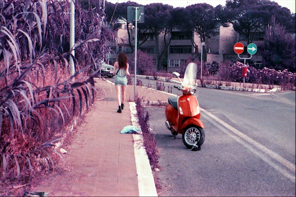 woman in teal tank top and blue denim shorts walking on sidewalk during daytime